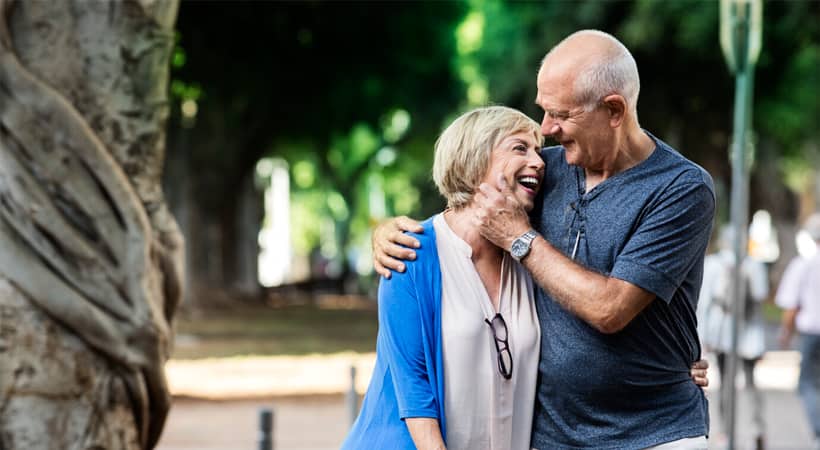 Et ektepar går ute, holder rundt hverandre og smiler