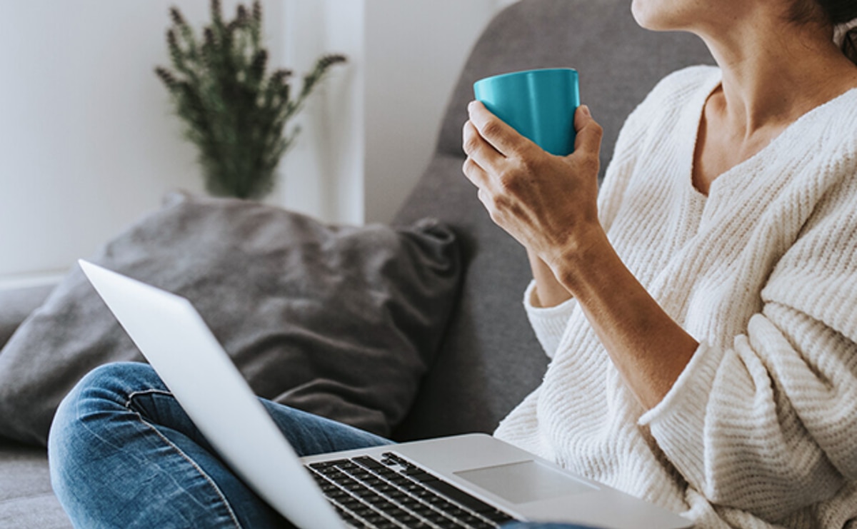 Kvinne i sofa med datamaskin på fanget
