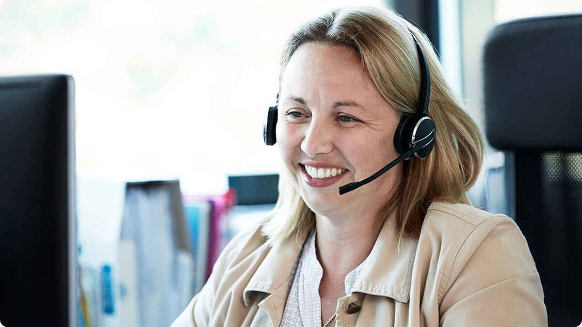 Kvinne med telefonheadset som smiler 