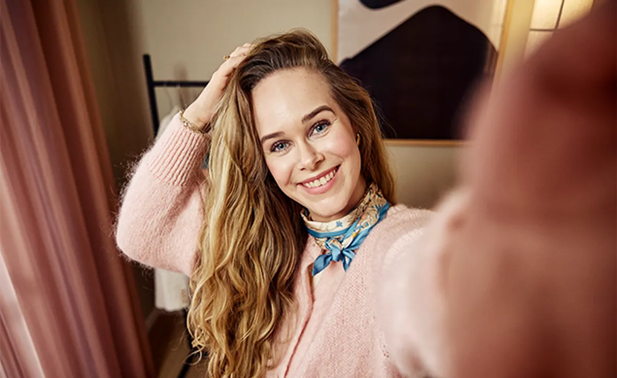 Cecilie smiler og holder en hånd i håret