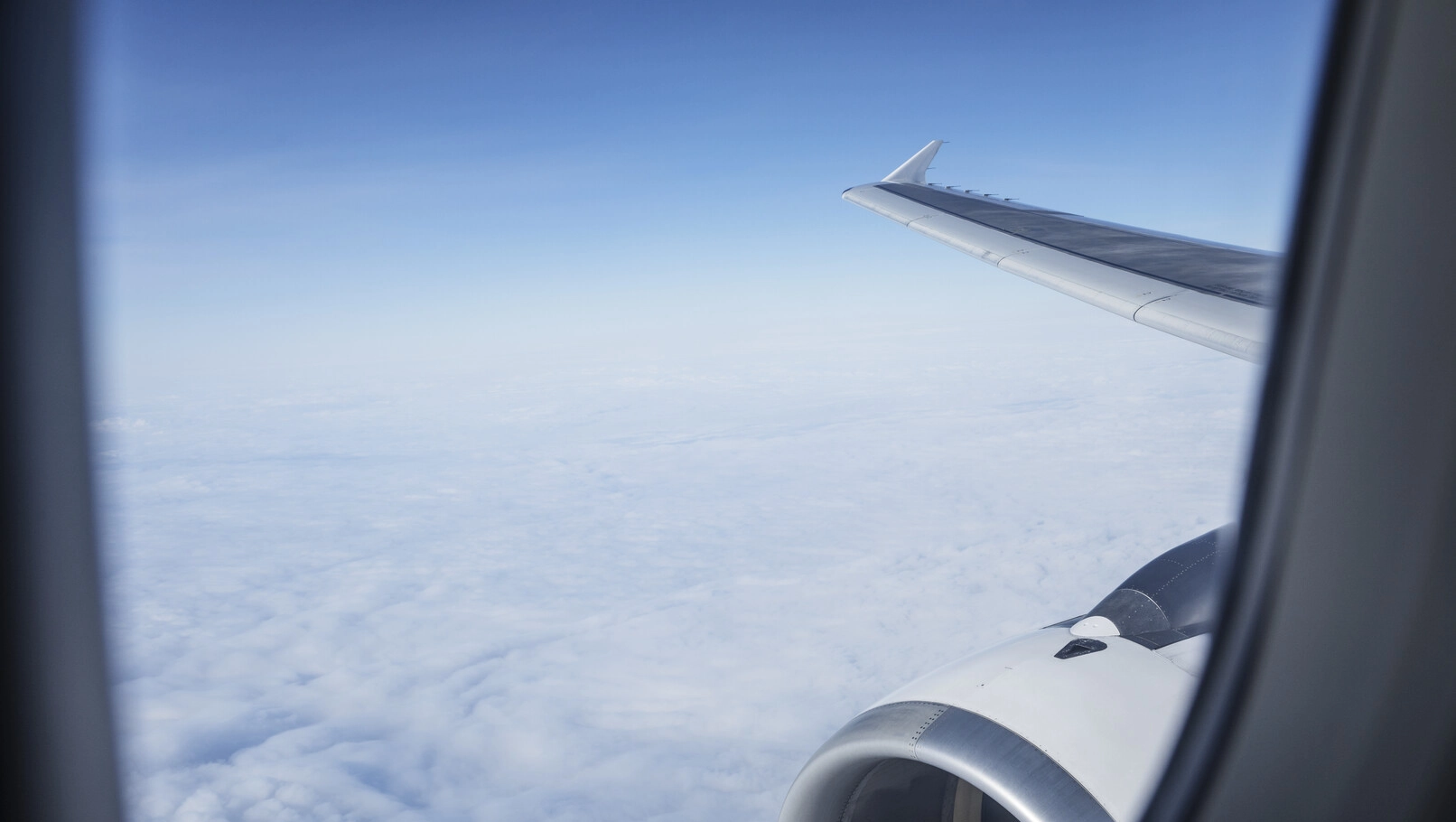 Flyutsikt gjennom vinduet med blå himmel og skyer